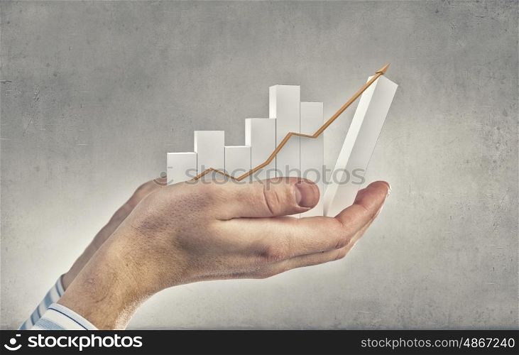 Financial growth. Close up of hand holding growing graph arrow
