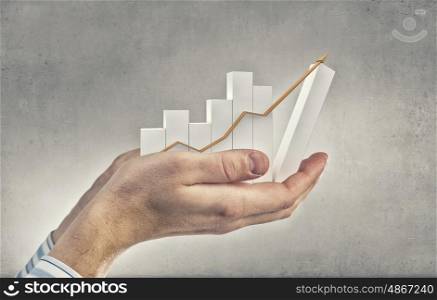 Financial growth. Close up of hand holding growing graph arrow