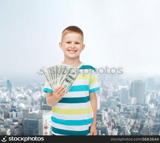 financial, planning, childhood and concept - smiling boy holding dollar cash money in his hand over city background