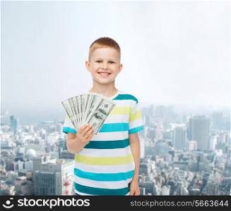 financial, planning, childhood and concept - smiling boy holding dollar cash money in his hand over city background