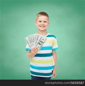 financial, planning, childhood and educational concept - smiling boy holding dollar cash money in his hand over green board background