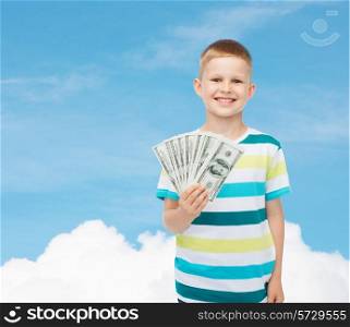 financial, planning, childhood and educational concept - smiling boy holding dollar cash money in his hand over blue sky background