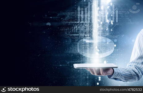 Financial report. Tablet pc in hand of businessman and financial graphics on wall