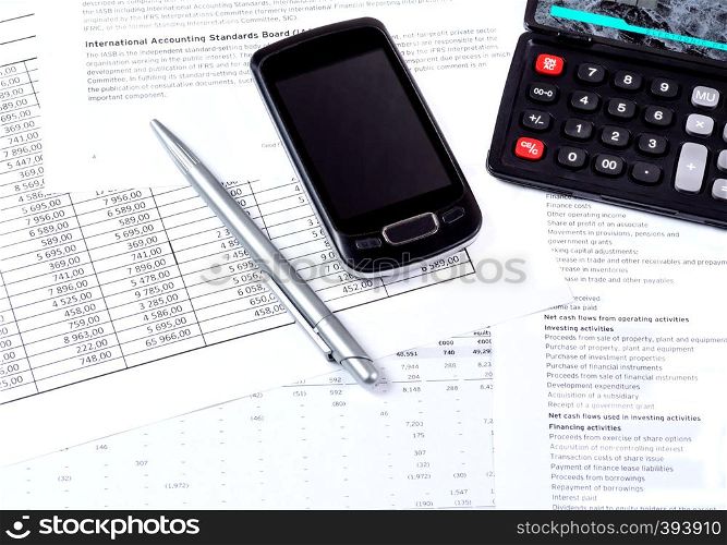 Financial tables, a black calculator, a ballpoint pen and glasses on the table. Economic analysis of financial documents