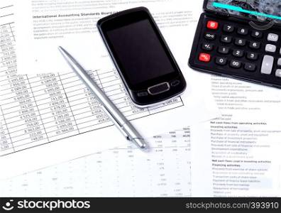 Financial tables, a black calculator, a ballpoint pen and glasses on the table. Economic analysis of financial documents