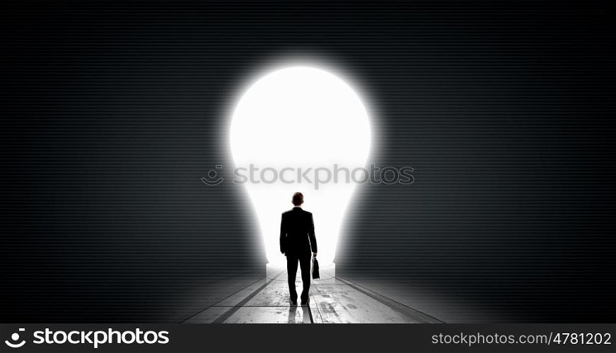 Find great bright idea. Back view of businessman looking at big glowing light bulb