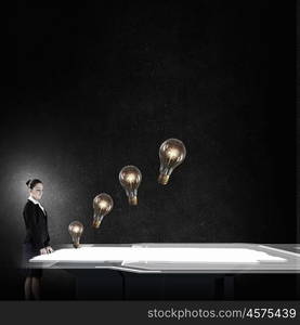 Find your idea. Young businesswoman looking at glass light bulb