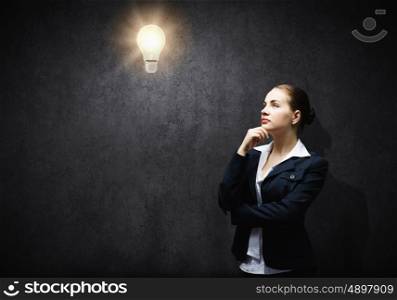 Finding inspiration. Image of thoughtful businesswoman looking at light bulb