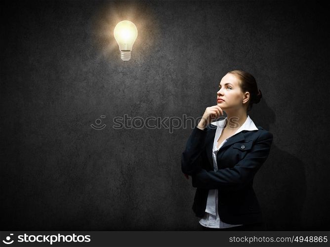 Finding inspiration. Image of thoughtful businesswoman looking at light bulb