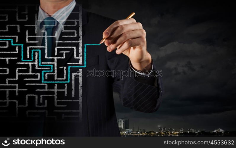 Finding solution. Close up of businessman drawing way out of labyrinth