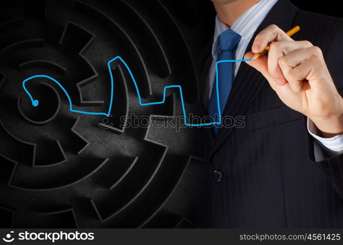 Finding solution. Close up of businessman drawing way out of labyrinth