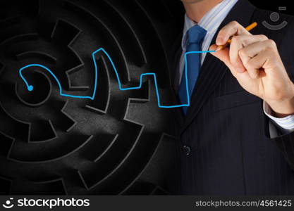 Finding solution. Close up of businessman drawing way out of labyrinth