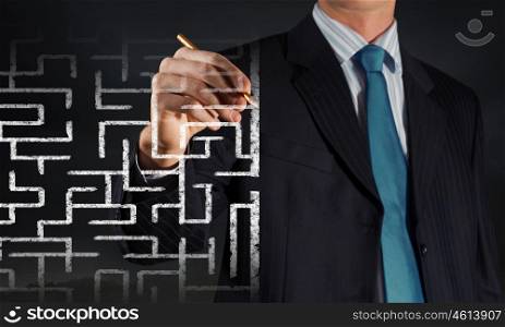 Finding solution. Close up of businessman drawing way out of labyrinth