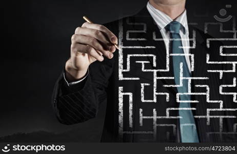 Finding solution. Close up of businessman drawing way out of labyrinth