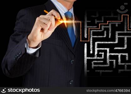 Finding solution. Close up of businessman drawing way out of labyrinth