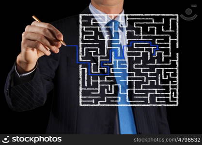 Finding solution. Close up of businessman drawing way out of labyrinth