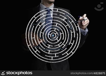 Finding solution. Close up of businessman drawing way out of labyrinth