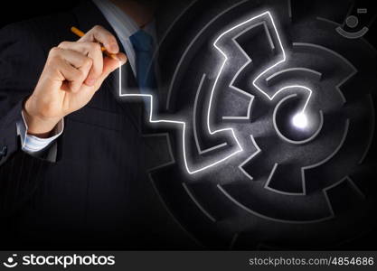 Finding solution. Close up of businessman drawing way out of labyrinth