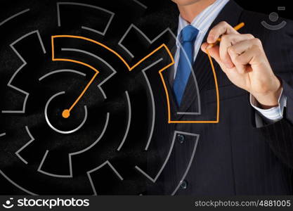 Finding solution. Close up of businessman drawing way out of labyrinth