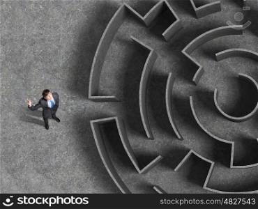 Finding solution. Top view of businessman standing near the enter of labyrinth