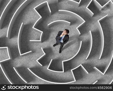 Finding the solution. Top view of successful businessman standing in center of labyrinth