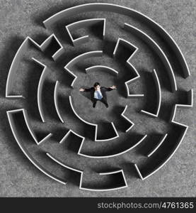 Finding the solution. Top view of successful businessman standing in center of labyrinth