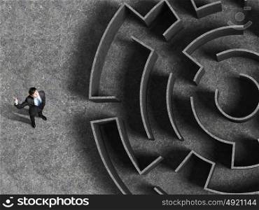 Finding the solution. Top view of successful businessman standing near the entrance of labyrinth
