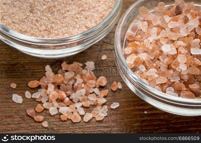 fine and coarse crystals of pink Himalayan salt in glass bowls on rustic wood