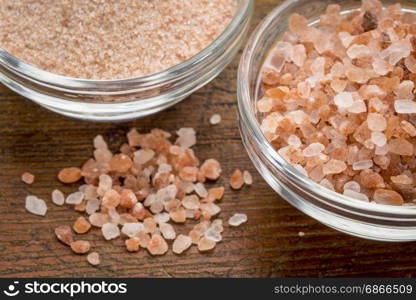 fine and coarse crystals of pink Himalayan salt in glass bowls on rustic wood