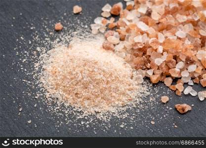 fine and coarse crystals of pink Himalayan salt on gray slate stone
