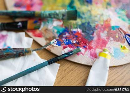 fine art, creativity and artistic tools concept - close up of palette knife or painting spatula, brushes and paint tube. palette knife or spatula, brushes and paint tube