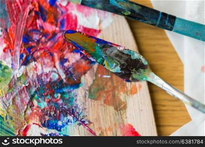 fine art, creativity and artistic tools concept - close up of palette knife or painting spatula and paintbrush from top. palette knife or painting spatula and paintbrush