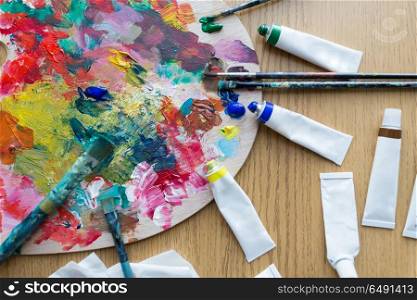 fine art, creativity and artistic tools concept - close up of palette, brushes and paint tubes on table. palette, brushes and paint tubes on table. palette, brushes and paint tubes on table