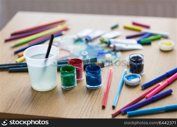 fine art, creativity and artistic tools concept - gouache colors, felt tip pens and pencils on table. gouache colors, felt tip pens and pencils on table
