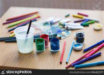 fine art, creativity and artistic tools concept - gouache colors, felt tip pens and pencils on table. gouache colors, felt tip pens and pencils on table