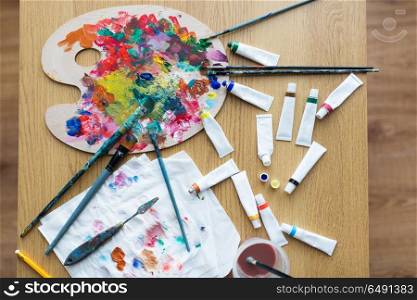 fine art, creativity and artistic tools concept - palette, brushes and paint tubes on table. palette, brushes and paint tubes on table. palette, brushes and paint tubes on table