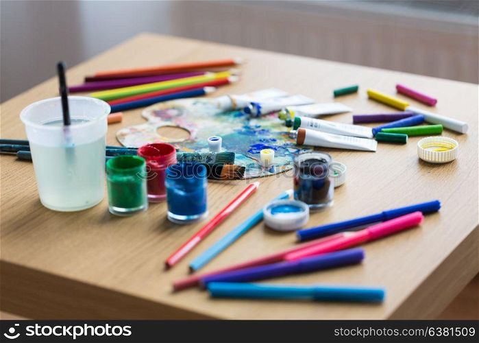 fine art, creativity and artistic tools concept - palette, brushes, paint tubes and gouache colors on table. palette, brushes and paint tubes on table