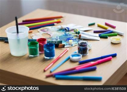 fine art, creativity and artistic tools concept - palette, brushes, paint tubes and gouache colors on table. palette, brushes and paint tubes on table