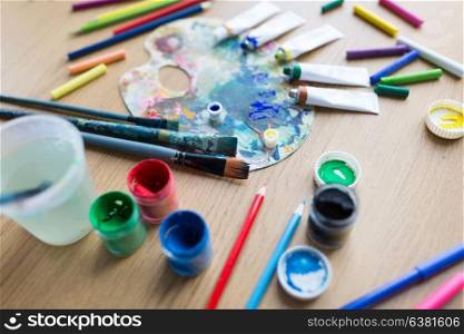 fine art, creativity and artistic tools concept - palette, brushes, paint tubes and gouache colors on table. color palette, brushes and paint tubes on table