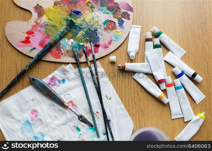 fine art, creativity and artistic tools concept - palette knife, brushes and paint tubes on table. palette knife, brushes and paint tubes on table
