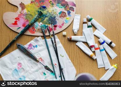 fine art, creativity and artistic tools concept - palette knife, brushes and paint tubes on table. palette knife, brushes and paint tubes on table
