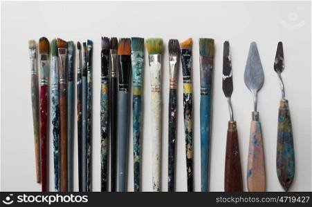 fine art, creativity and artistic tools concept - palette knives or painting spatulas and paintbrushes from top. palette knives or painting spatulas and brushes. palette knives or painting spatulas and brushes
