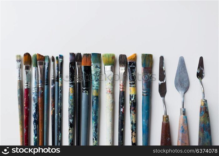 fine art, creativity and artistic tools concept - palette knives or painting spatulas and paintbrushes from top. palette knives or painting spatulas and brushes