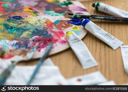 fine art, creativity, painting and artistic tools concept - acrylic color or paint tubes, palette and brushes. acrylic color or paint tubes and palette