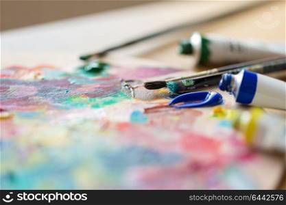 fine art, creativity, painting and artistic tools concept - acrylic color or paint tubes, palette and brushes. acrylic color or paint tubes and palette