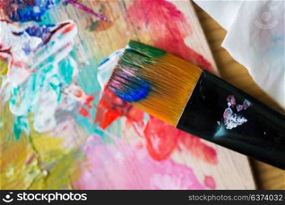 fine art, creativity, painting and artistic tools concept - close up of color palette and brush with paint. close up of color palette and brush with paint
