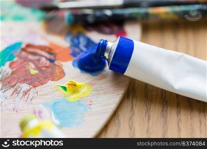 fine art, creativity, painting and artistic tools concept - close up of acrylic color or paint tube and palette. acrylic color or paint tubes and palette