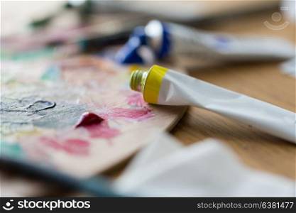 fine art, creativity, painting and artistic tools concept - close up of acrylic color or paint tubes and palette. acrylic color or paint tubes and palette