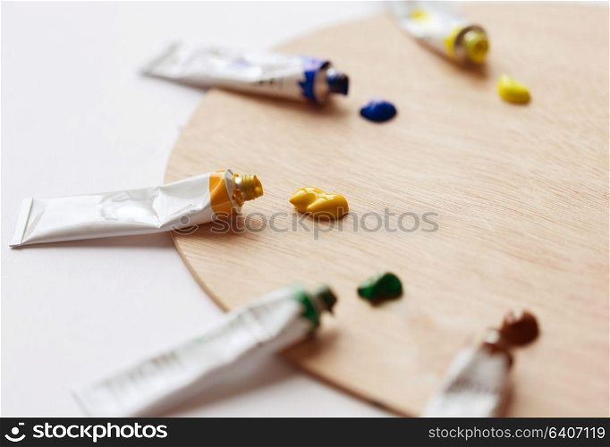 fine art, creativity, painting and artistic tools concept - close up of palette and acrylic color tubes or paint. palette and acrylic color tubes or paint