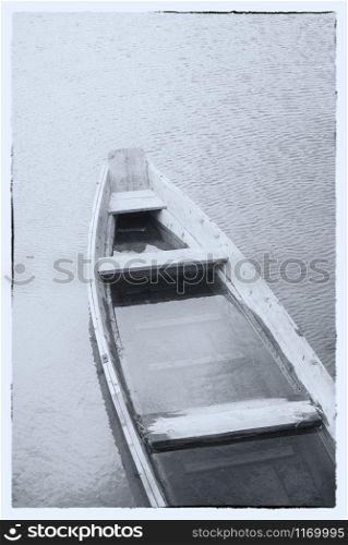 Fine art image in black & white. A wooden boat on a misty lake.